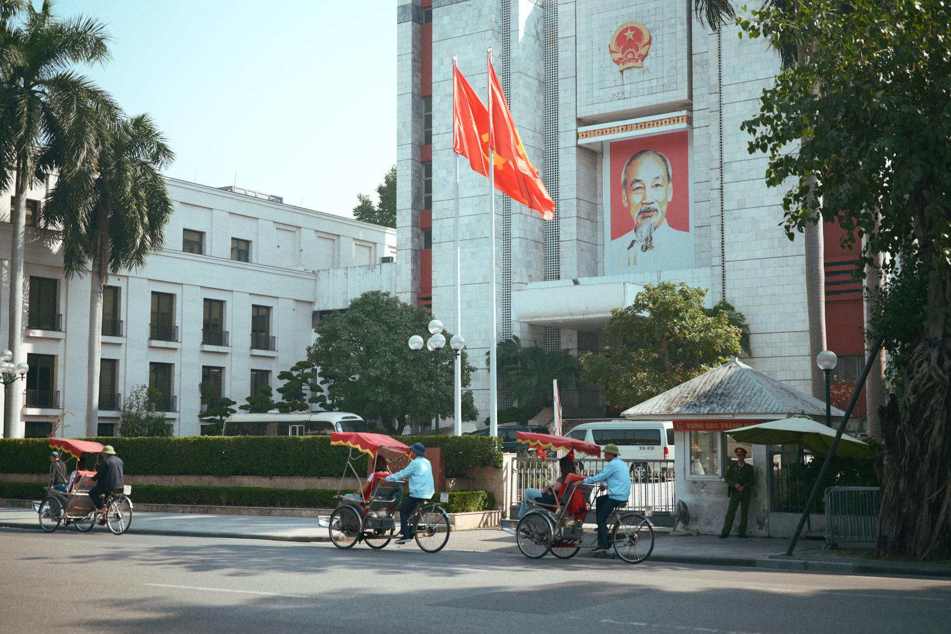 hanoi street scene with cyclo riders and flags