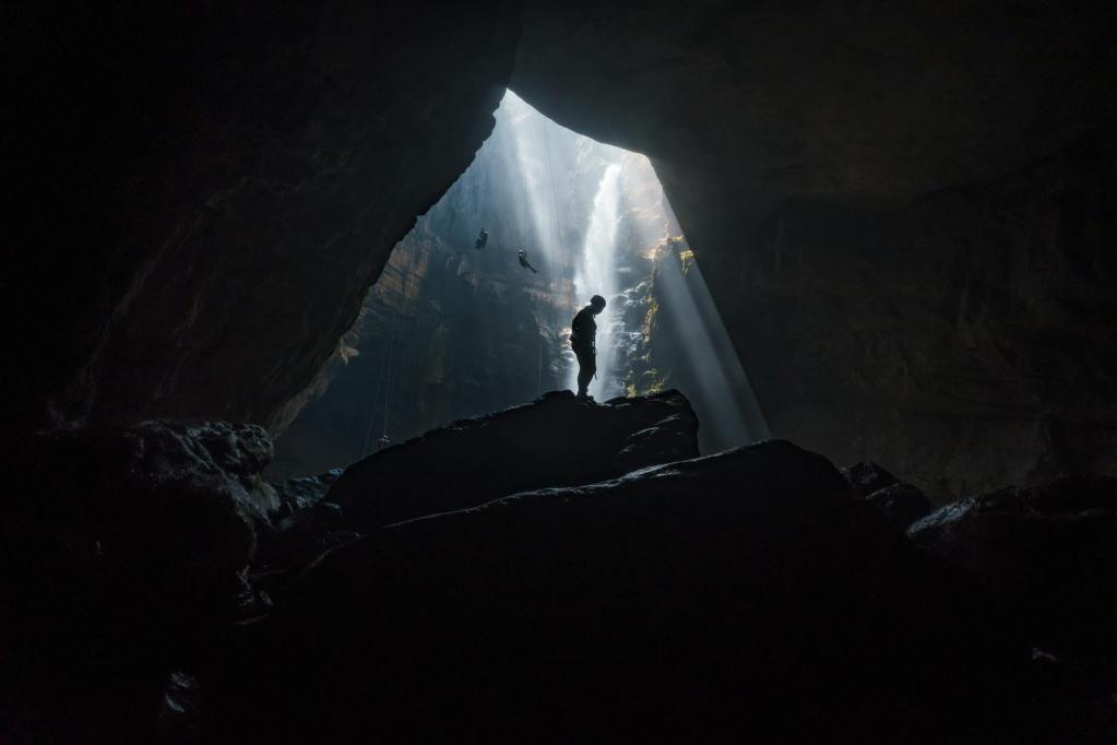 adventurer in majestic cave with sunbeams Son Doong