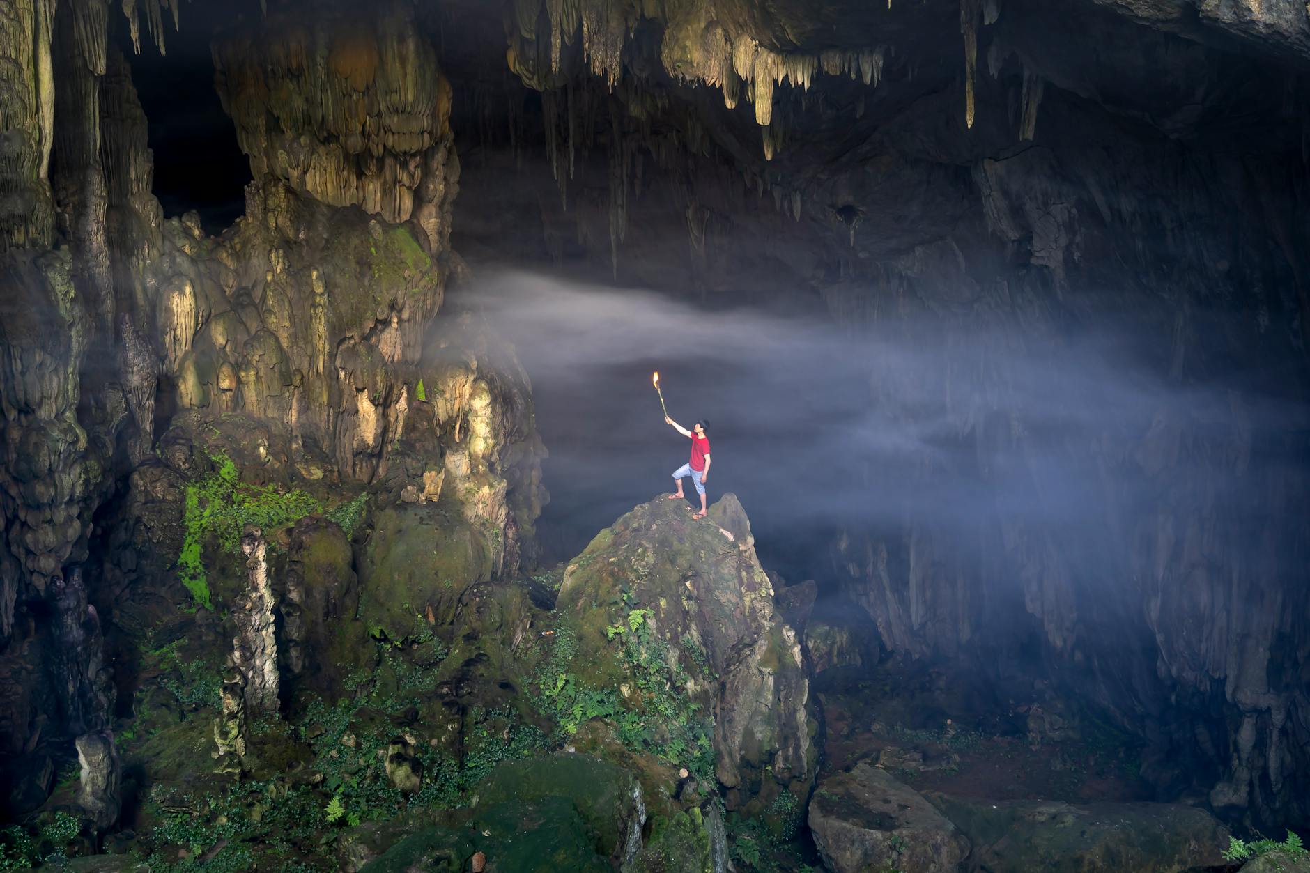 man with a torch standing in a cave