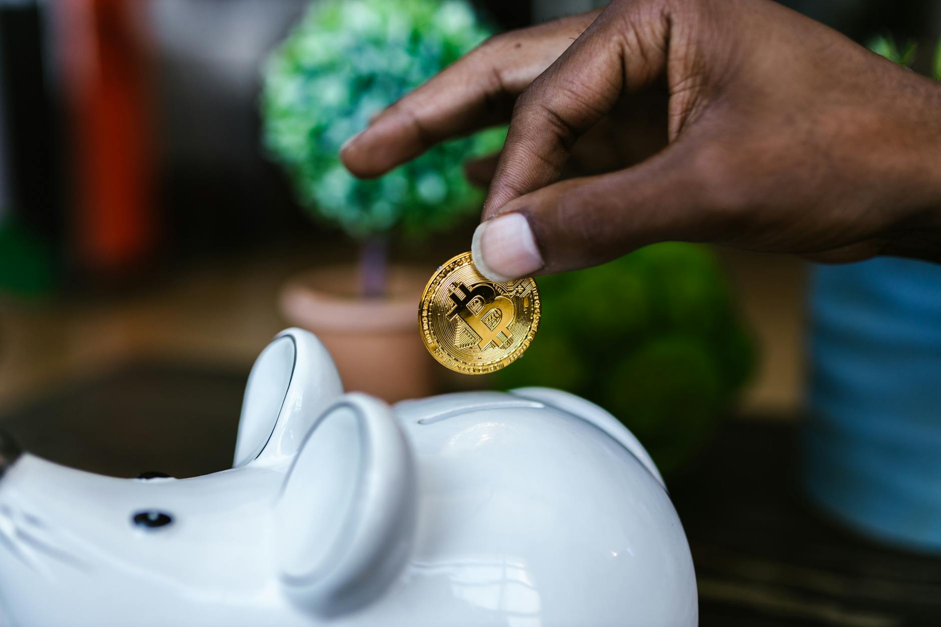 a hand inserting the gold coin in the piggy bank
