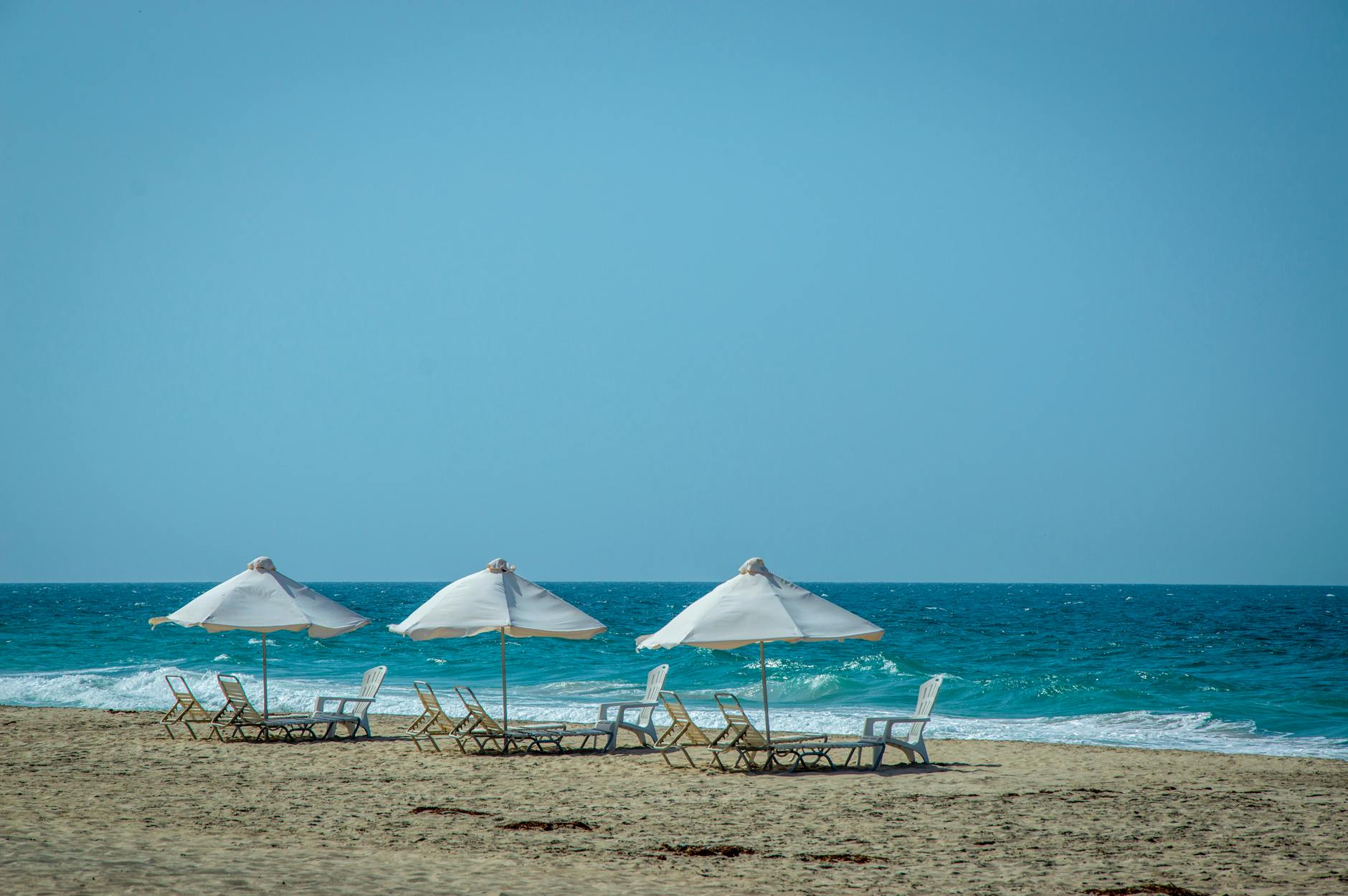 sunloungers on beach along blue ocean