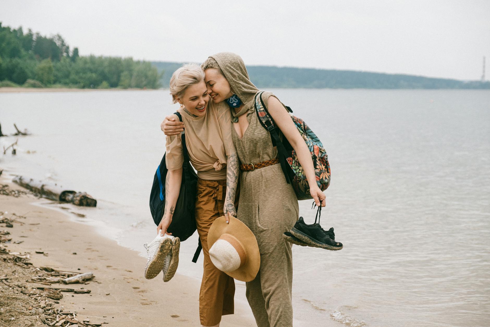 photo of women embracing while standing on beach