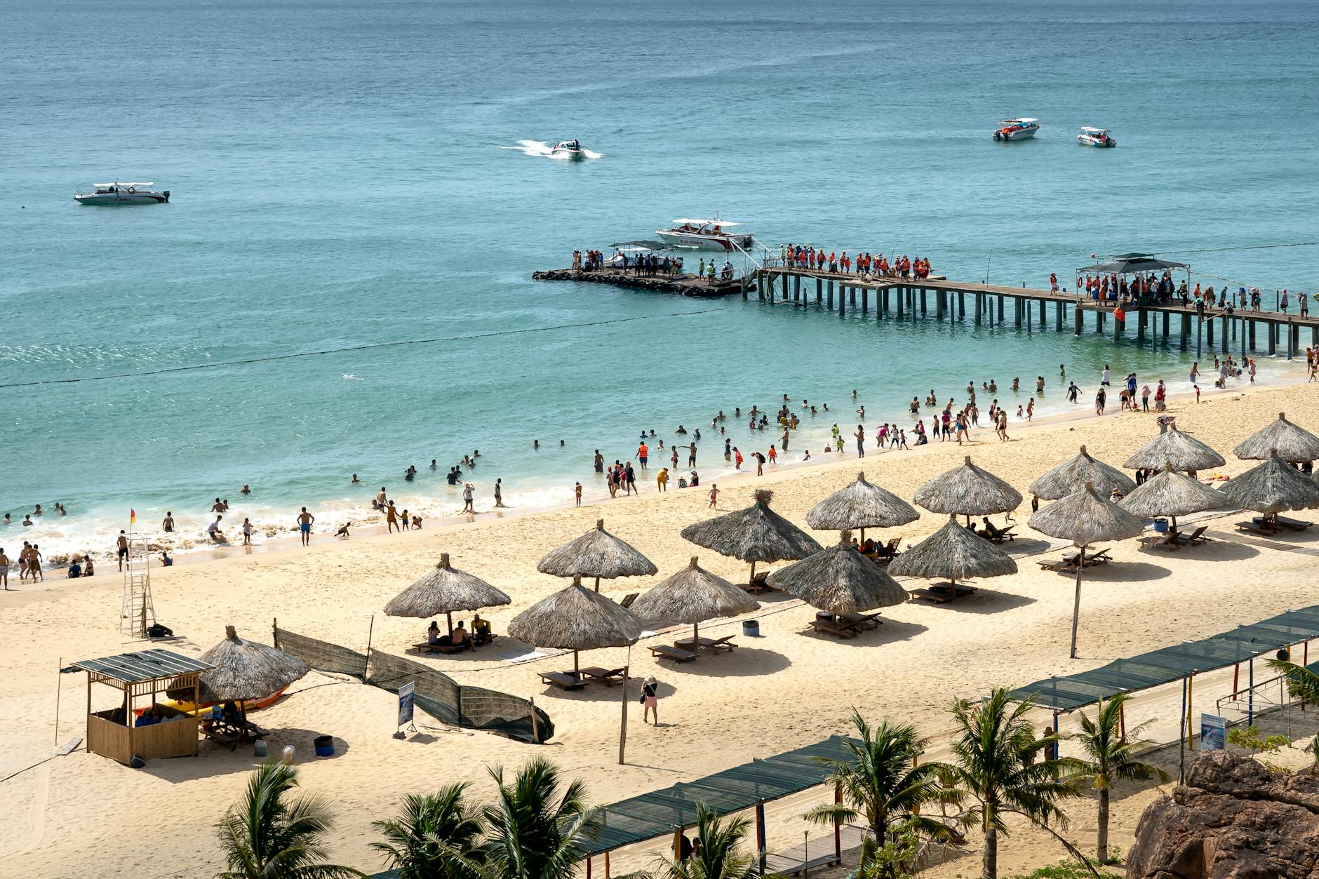 crowded sandy beach with straw umbrellas