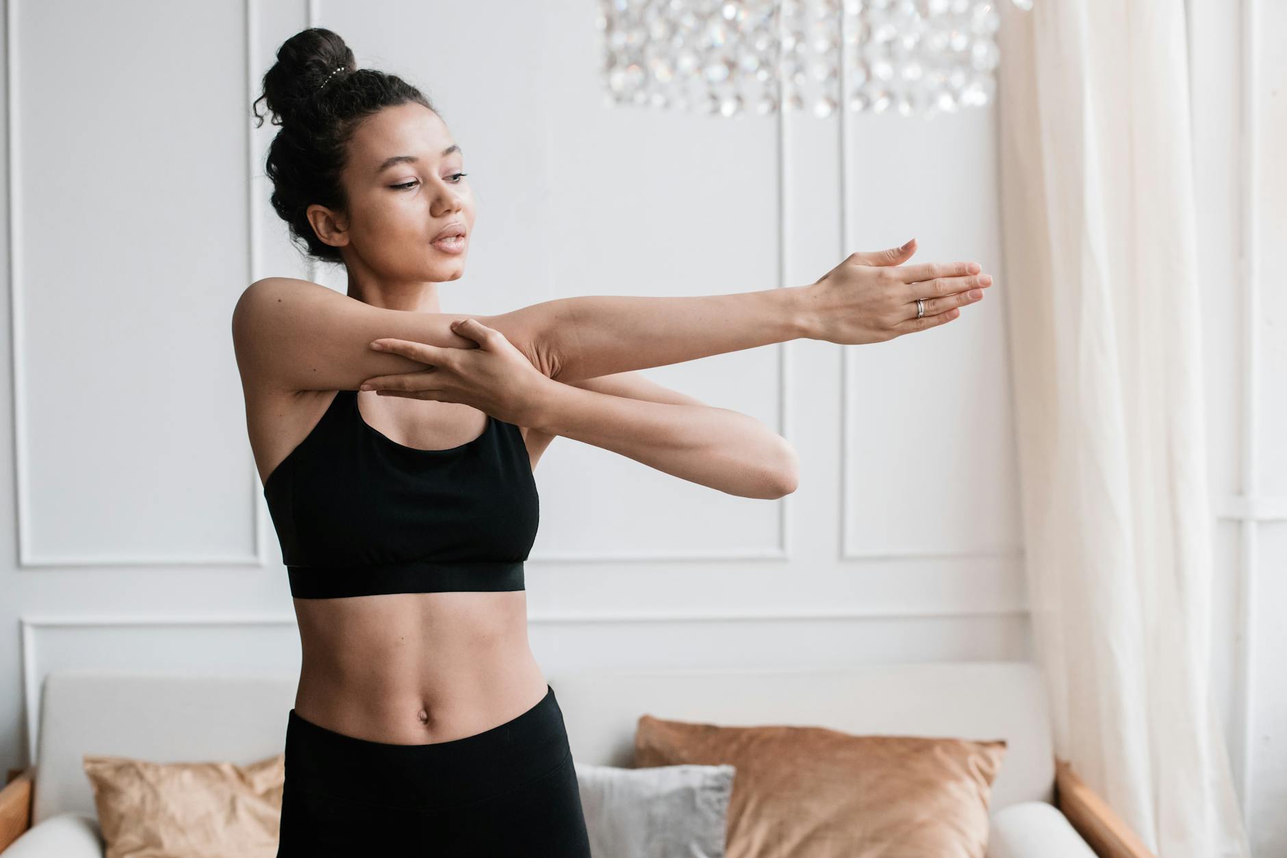 woman in a black sports bra stretching her arm