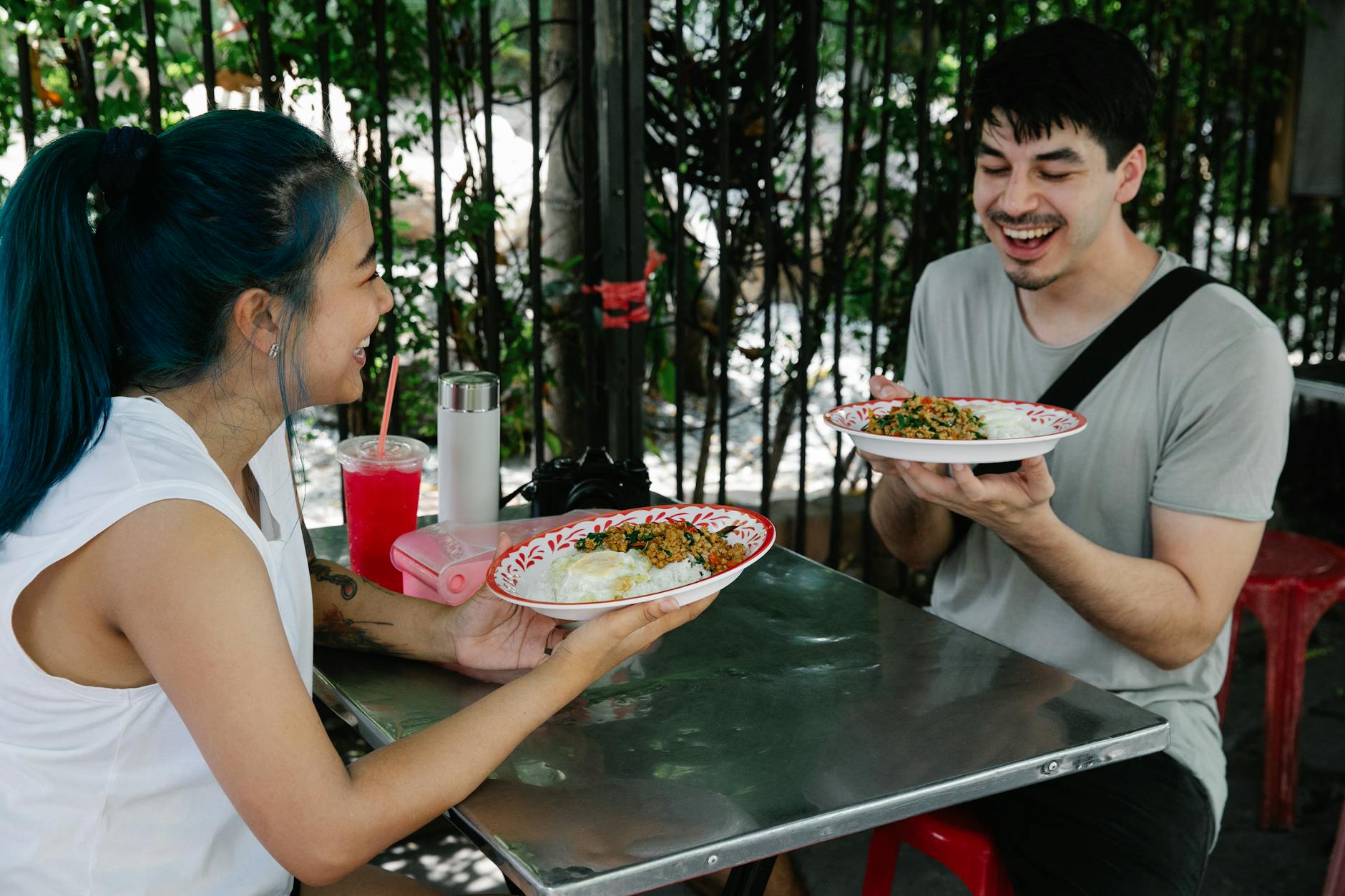 cheerful diverse couple with dishes in cafe