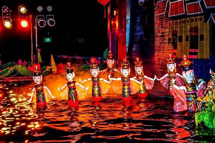 Golden-Dragon-Water-Puppet Traditional water puppets performing on a lit water stage with colorful reflections and theater lights