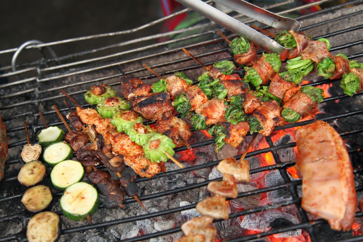 Grilled skewers featuring meat and assorted vegetables, including zucchini and green peppers, cooking over hot coals.