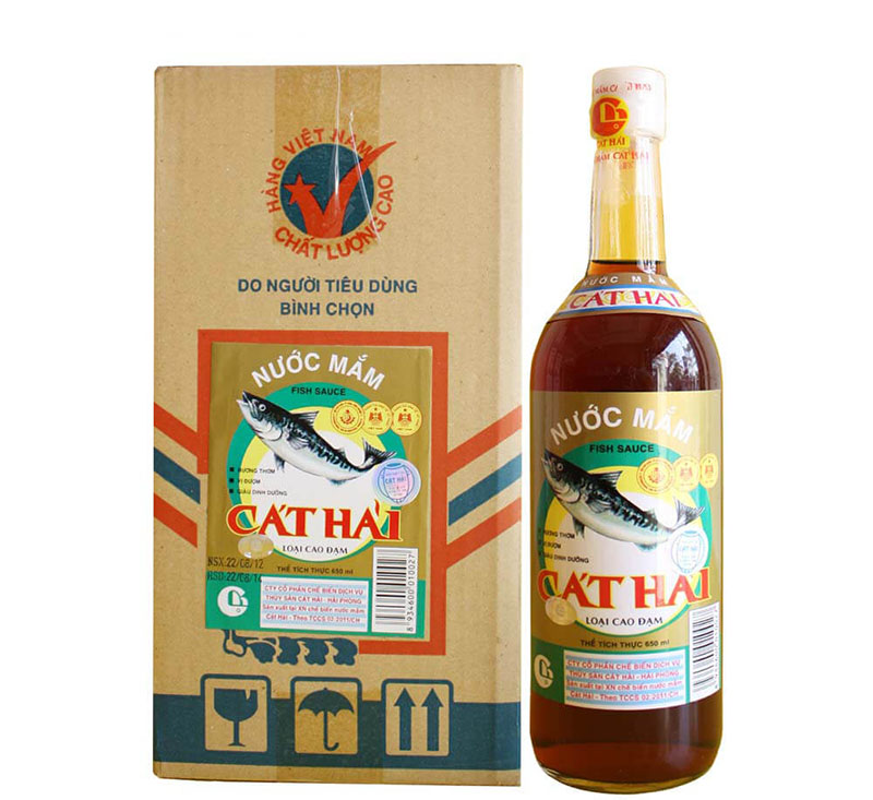 A bottle of fish sauce labeled 'Cát Hải' alongside a box with a fish illustration, emphasizing its quality.
